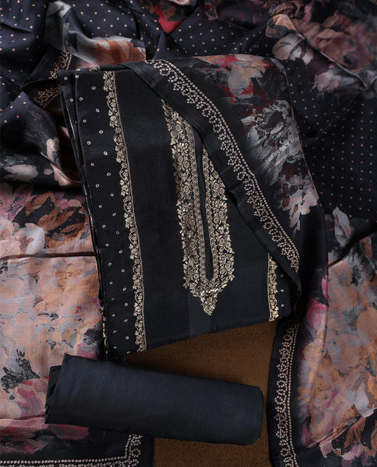 Black colour churidhar material highlighted with elegant zari embroidery on the neckline, paired with a plain matching bottom and a floral printed dupatta with dotted accents.
