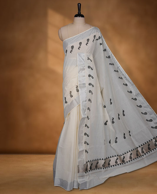 Off-white colour cotton Kerala saree featuring a subtle silver kasavu border, adorned with elegant black peacock motifs across the body and pallu, finished with a coordinated blouse for a refined, contemporary look.