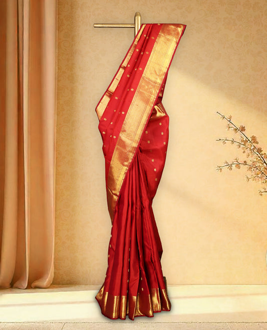 Deep red colour pure Kancheepuram traditional saree featuring gold zari Mayoora Chakra motifs across the body, enhanced with a classic traditional border and a grand pallu woven with Kuttumayil and Sayagata designs, paired with a matching blouse.