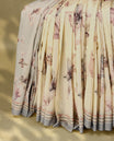 Cream colour semi silk printed saree adorned with pastel onion floral motifs across the body, finished with a light Blue and light Brown striped border, with matching blouse