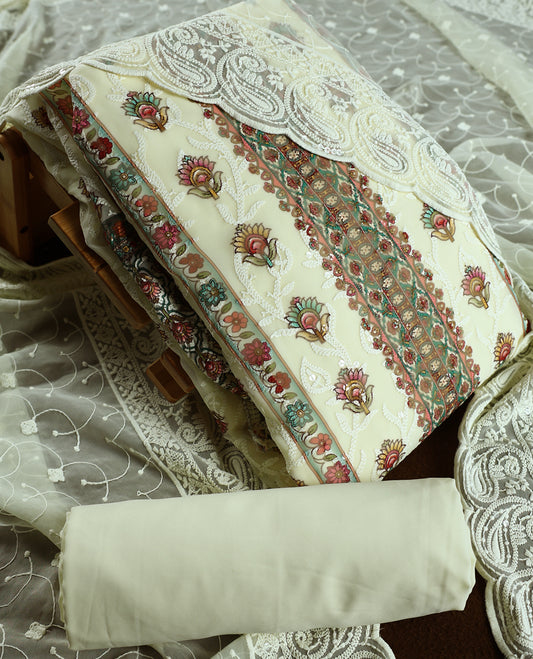 Cream churidhar material with embroidered green colour neck work, white threadwork on the body, and multicolor floral motifs in pink, green & yellow & Comes with matching plain bottom and embroidered dupatta.