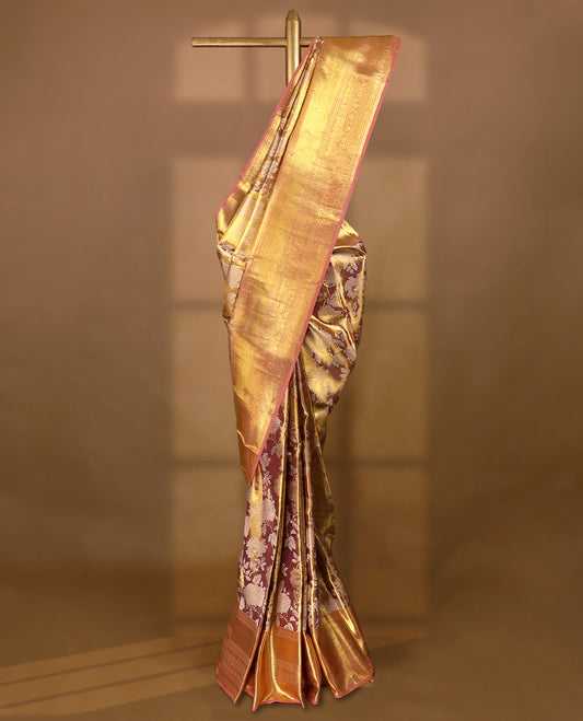 Golden Colour Kancheepuram tissue silk saree adorned with intricate silver and gold zari floral work on the body, elegantly accentuated by a pastel peach traditional Chakkram and floral design border, and paired with a matching blouse.