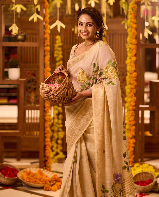 Beige colour Kerala saree crafted in soft fabric, adorned with elegant yellow and purple floral embroidery across the body and pallu, highlighted with a subtle woven zari border, paired with a matching blouse