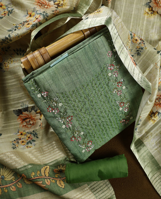 Light green colour churidhar material adorned with floral embroidery and sewn glass beads on the yoke, paired with a plain green bottom and a beige dupatta featuring floral prints.