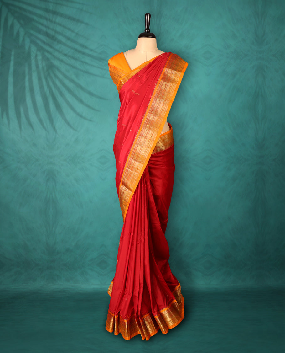 Deep Red colour Traditional Kancheepuram Silk saree with small gold motifs on body, orange colour traditional border with intricate gold zari weaving, grand zari pallu, perfect for Bharatanatyam, with matching blouse.
