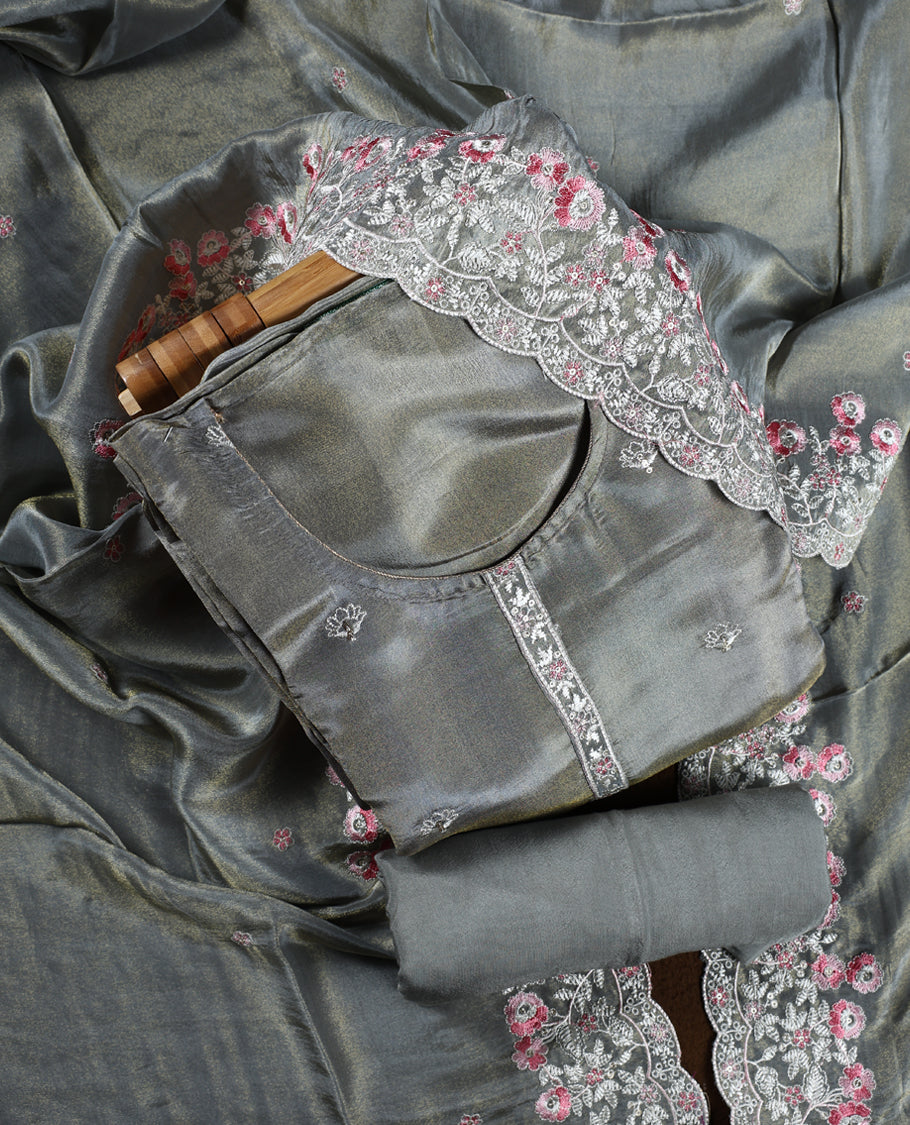Grey colour churidar material adorned with delicate floral thread embroidery in white and pink, paired with a plain matching bottom and embroidered dupatta, perfect for festive occasions and celebrations.