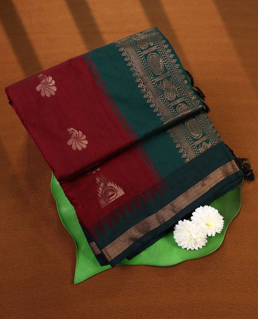 Brick red and Dark Green Kalyani cotton saree featuring delicate golden floral and peacock motifs, highlighted with an intricately woven zari border and pallu, paired with a matching blouse