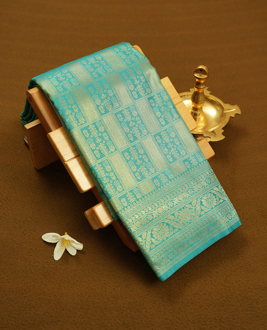 Aqua Blue colour semi silk brocade saree featuring intricate Gold Square patterns across the body, complemented by a Self colour woven border and pallu, paired with a matching blouse.