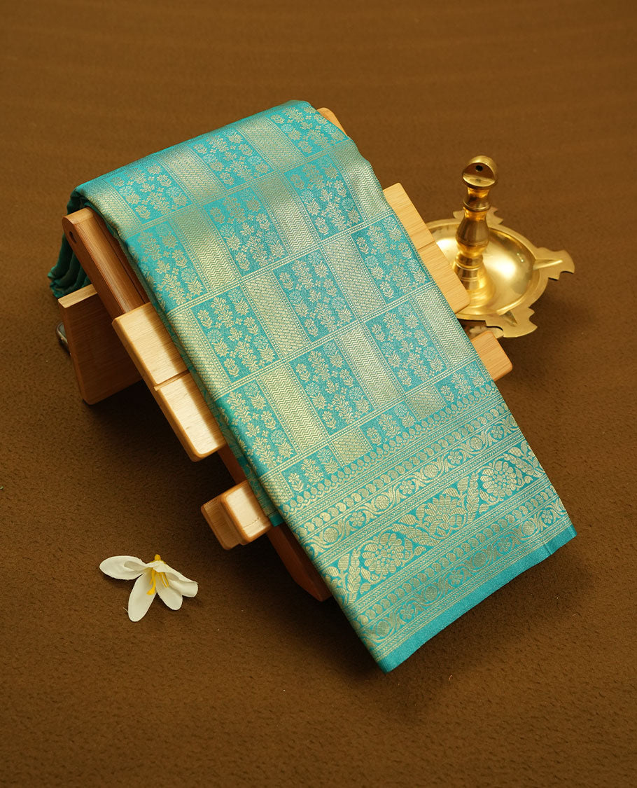 Aqua Blue colour semi silk brocade saree featuring intricate Gold Square patterns across the body, complemented by a Self colour woven border and pallu, paired with a matching blouse.