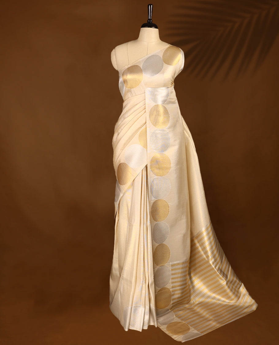 Muted gold Colour soft tissue Kerala saree featuring Plain body, Gold nad silver zari circle motifs on border, paired with a matching blouse.