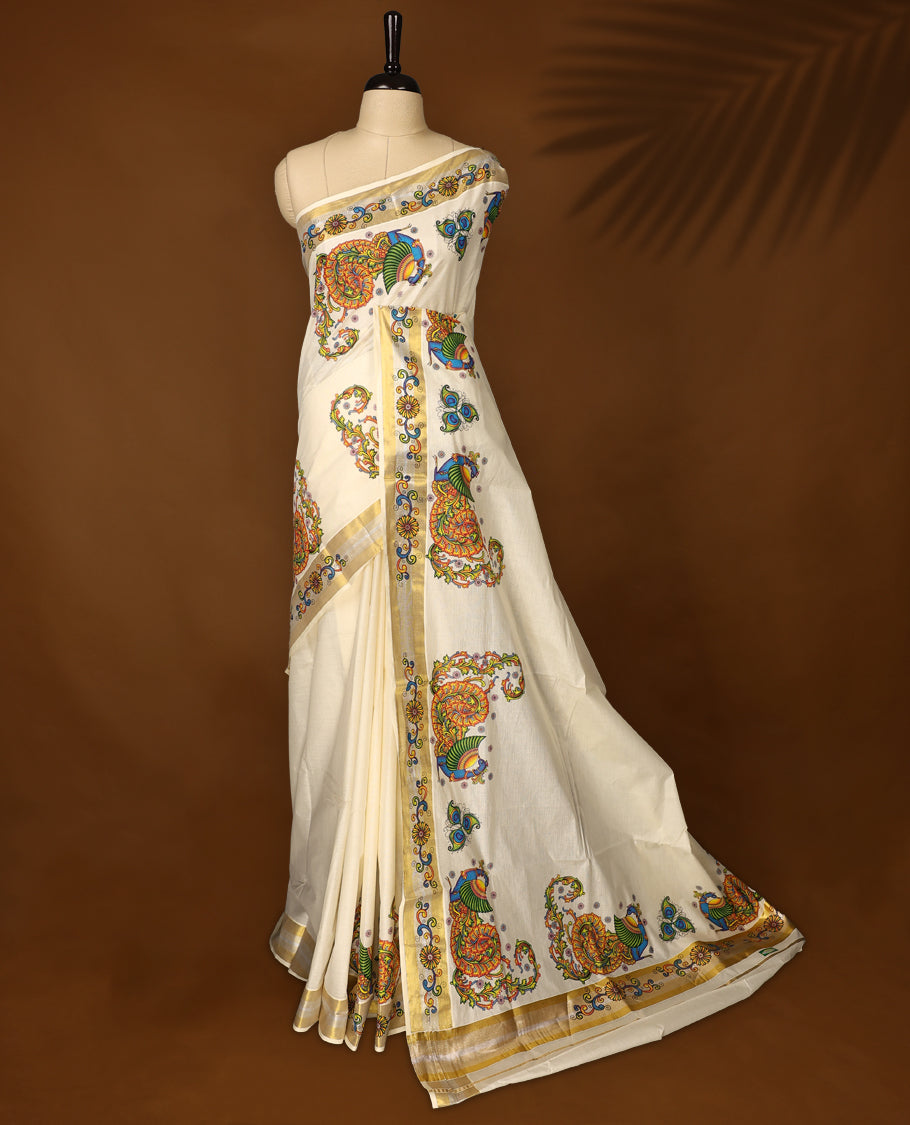 Off white colour Kerala cotton saree featuring vibrant peacock & floral prints, enhanced with a traditional golden kasavu border and A festive ready drape paired with a matching blouse, perfect for graceful celebrations.