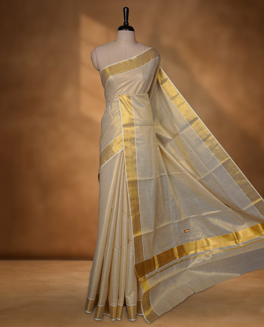 Off-white colour tissue Kerala saree with a timeless gold kasavu border, featuring a subtle striped weave across the body and pallu, paired with a matching blouse.