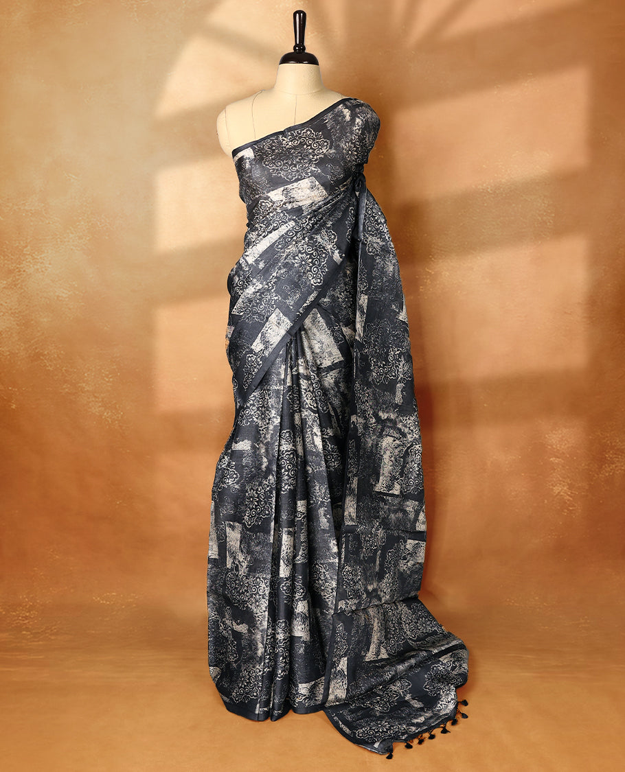 Black colour pure tussar silk light weight saree with full body abstract floral print, no defined border and pallu, paired with matching abstract printed blouse.