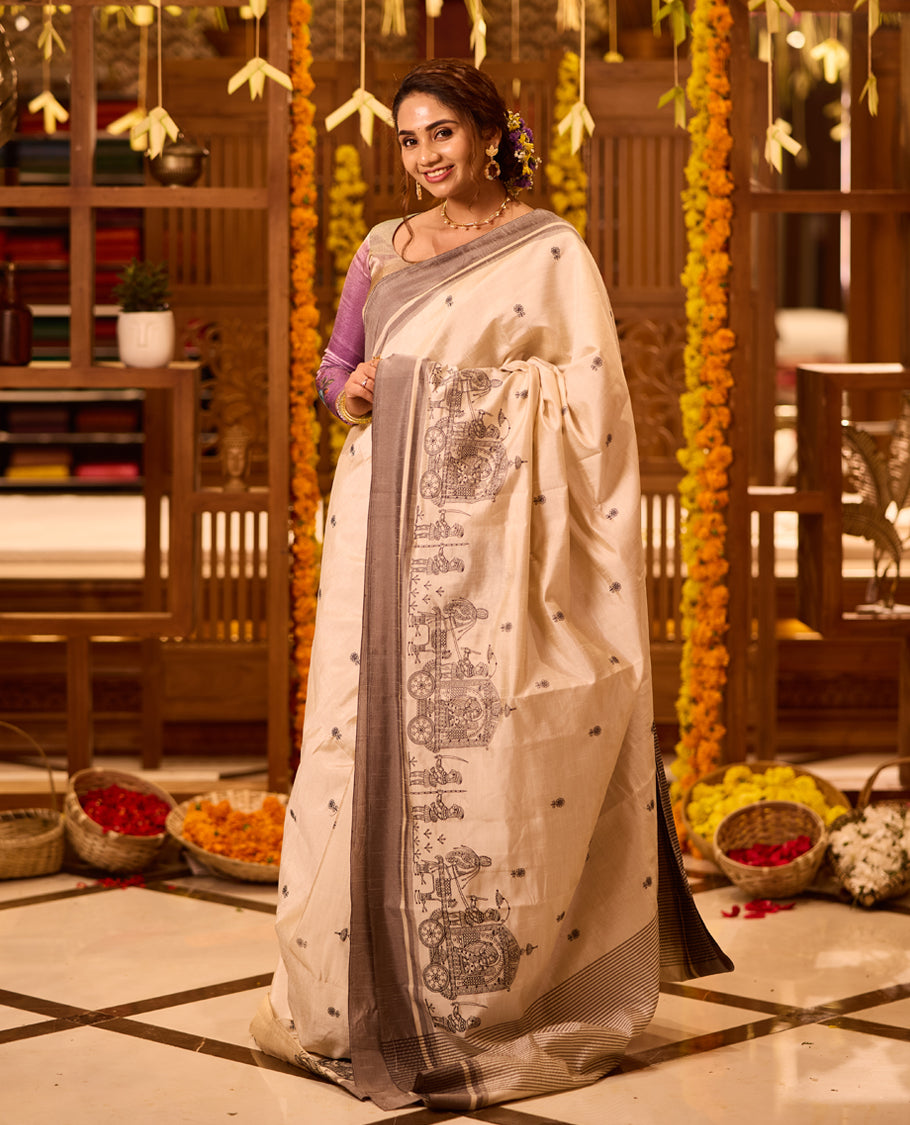 Off White colour Tussar saree adorned with small black woven motifs across the body, featuring an artistic temple chariot motif on the pallu, highlighted with a sleek grey border, paired with a matching blouse