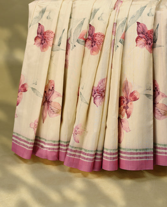 Cream colour semi silk printed saree adorned with soft pink floral motifs across the body, finished with a mauve and green striped border, with matching blouse