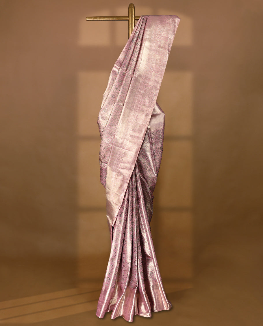 Pastel pink Colour Kancheepuram tissue silk saree adorned with intricate antique zari floral motifs on the body, beautifully complemented by traditional elephant and Chakkram design border, and paired with a matching blouse.