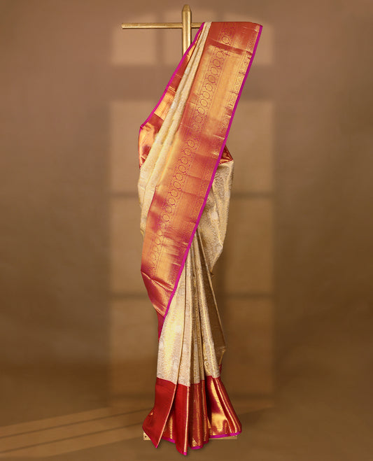 Golden Colour Kancheepuram tissue silk saree adorned with intricate silver and gold zari floral jaal work on the body, enhanced by a contrasting traditional floral kodi design border, paired with a matching blouse.