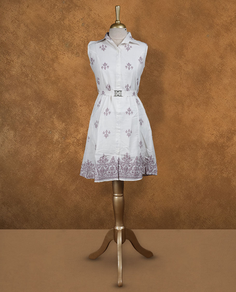 White sleeveless shirt dress with subtle mauve ethnic motifs, front button placket, matching waist belt with metal buckle, and ornate border print at hem.