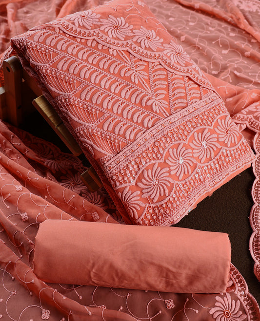 Charming peach pink colour churidhar material highlighted with intricate floral embroidery and delicate sequin accents, paired with a plain matching bottom and embroidered dupatta, perfect for festive gatherings and elegant occasions.