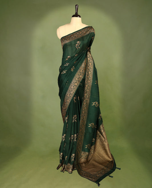 Dark Green colour semi Banaras tussar georgette saree embellished with antique zari flower motifs across the body, complemented by a rich Banaras border and paired with a matching blouse.