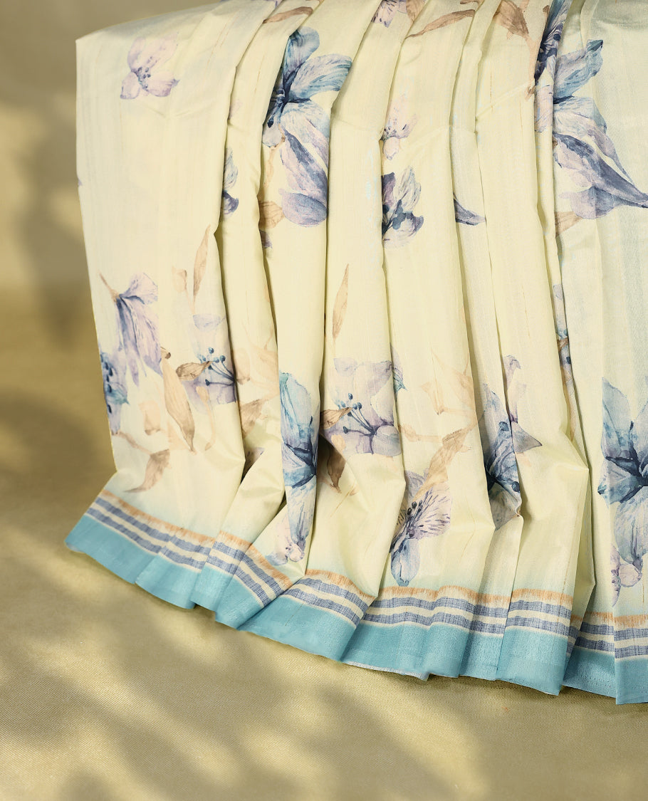 Cream colour semi silk printed saree adorned with soft Blue floral motifs across the body, finished with a soft Grey and light Brown striped border, with matching blouse