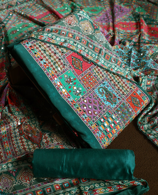 Green colour churidhar material with vibrant multicolour geometric and paisley prints, enhanced with delicate mirror work, paired with a plain matching bottom and bold printed dupatta, perfect for festive occasions.