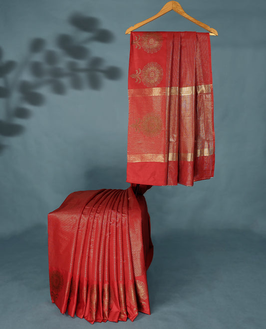 Red Colour Semi Tussar Silk saree featuring golden zari horizontal lines across the body, adorned with bold Floral motifs on the border, paired with a matching blouse.