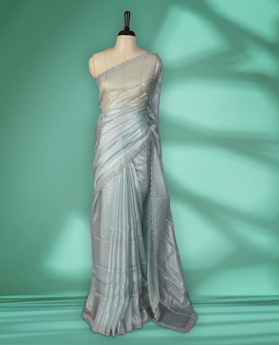 Icy blue colour net shimmer fancy saree adorned with subtle horizontal White stone patterns on the body, paired with a delicate stone worked border, with matching blouse