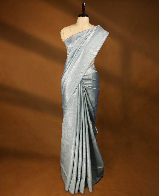 Pastel Grey coloured semi silk saree featuring a Silver coloured Zari Diamond design on the body, paired with a Self coloured border and matching blouse.