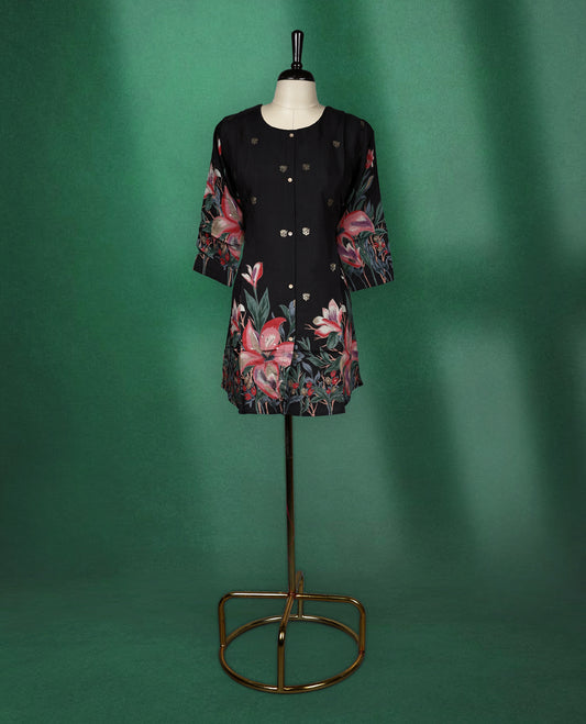 Black colour short kurti featuring a round neck and three quarter sleeves, adorned with soft golden motifs and a vibrant floral print along the hem and sleeves for a bold, elegant finish.
