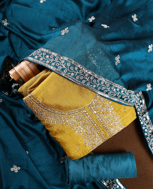Cookie brown colour churidhar top embellished with intricate silver embroidery, paired with a plain teal bottom and a rich teal dupatta featuring delicate butti work and ornate silver embroidered borders.