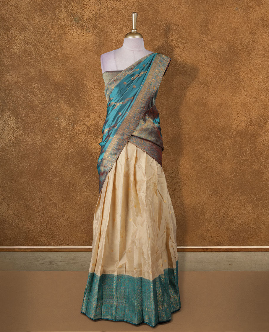 Chic semi stitched dhavani in cream and teal silk with delicate zari motifs and a rich pallu &  A perfect choice for traditional celebrations, blending elegance with customizable comfort and grace.