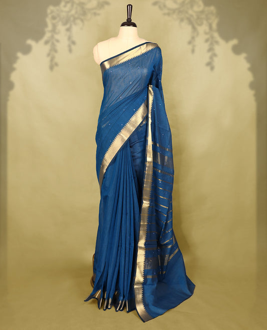 Blue colour Chanderi cotton saree featuring a subtly textured body with delicate buti work, complemented by a rich golden zari border with matching blouse