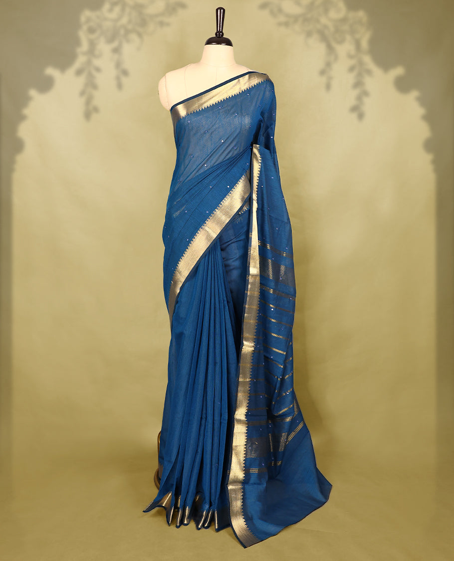 Blue colour Chanderi cotton saree featuring a subtly textured body with delicate buti work, complemented by a rich golden zari border with matching blouse
