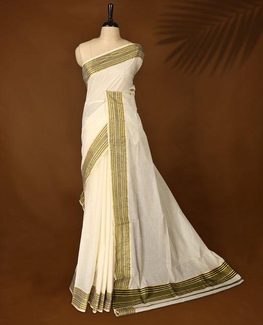 Elegant off white colour cotton Kerala saree with a soft cream body, adorned with traditional golden zari work,It features a green and gold striped border, offering a perfect blend of simplicity and festive charm & Includes blouse piece.