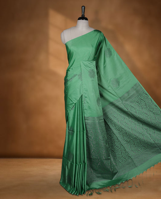 Jungle green colour semi soft silk saree adorned with delicate woven floral motifs on the body, complemented by a Self colour woven pallu with intricate detailing and tassel accents without border & Comes with a matching blouse piece.