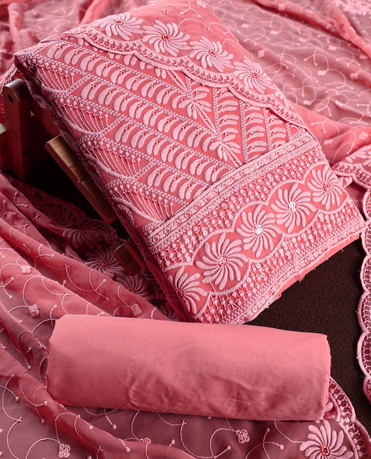 Charming coral pink churidhar material embellished with intricate floral embroidery and detailed thread patterns, paired with a plain matching bottom and embroidered dupatta, ideal for festive and elegant occasions.