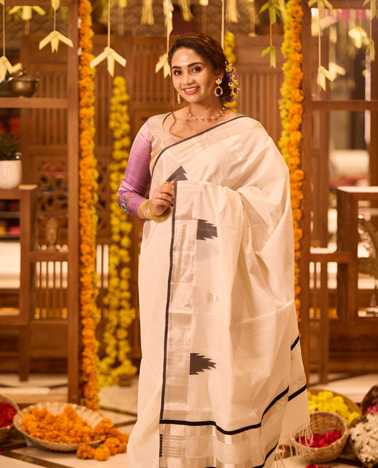 White colour Kerala Kasavu saree adorned with minimal black Temple motifs across the body, complemented by a sleek black border and zari detailing, paired with a matching blouse