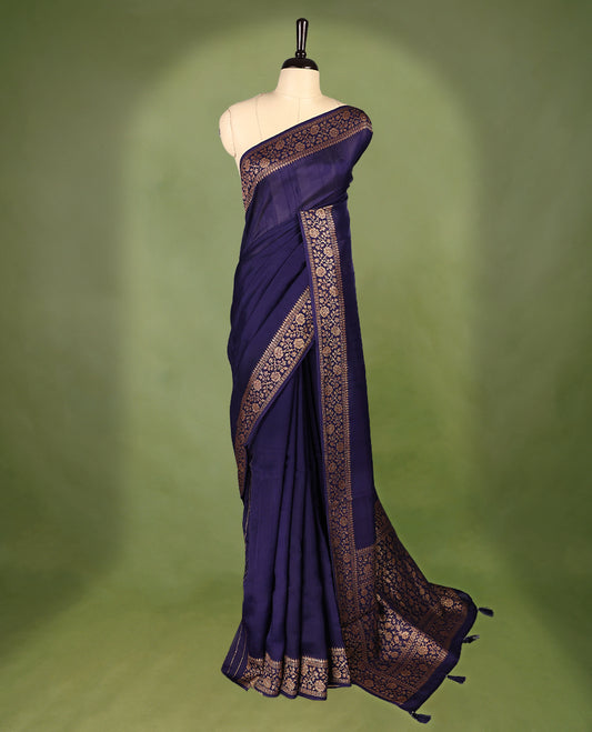 Navy Blue colour Tussar Banaras saree featuring a plain body, rich floral woven zari border and grand pallu, paired with a matching blouse for an elegant and regal traditional look.