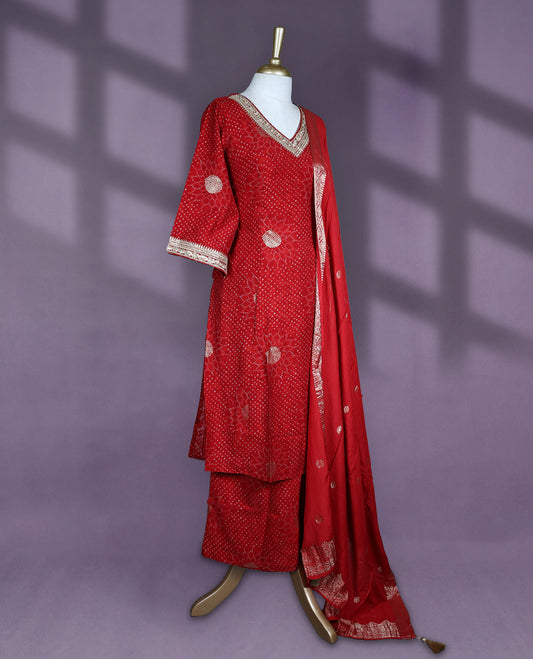 Deep red colour salwar set with V neck and elbow sleeves featuring bandhani inspired dotted pattern with gold motifs paired with matching bottom and dupatta with tassel detail