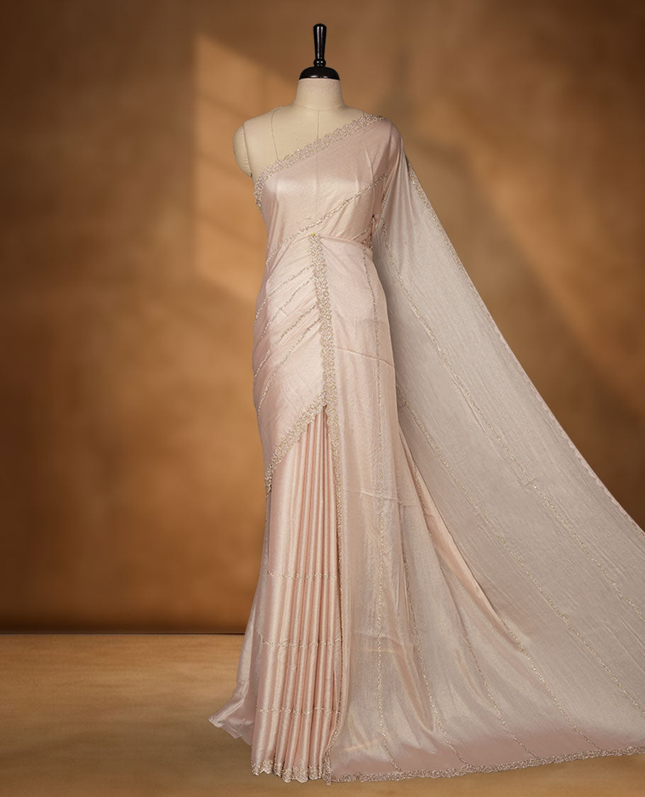 Pale pink colour net shimmer fancy saree adorned with scattered gold stone buttas all over the body, paired with a delicate stone worked border and matching blouse.