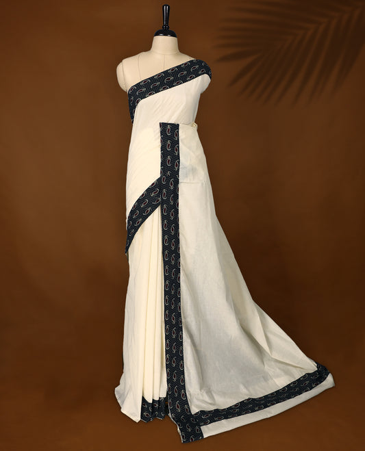 Off white colour cotton Kerala saree accentuated with a black printed border featuring red paisley motifs and delicate white dotted patterns, paired with a matching printed blouse for a classic ethnic charm