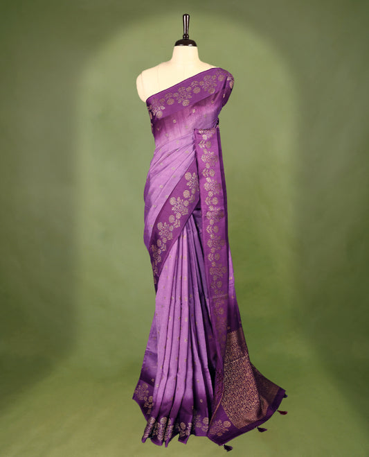 Lavender and purple double shade semi Banaras Tussar Georgette saree adorned with elegant antique gold zari floral motifs across the body, featuring a detailed woven border and grand pallu, paired with a matching blouse piece.