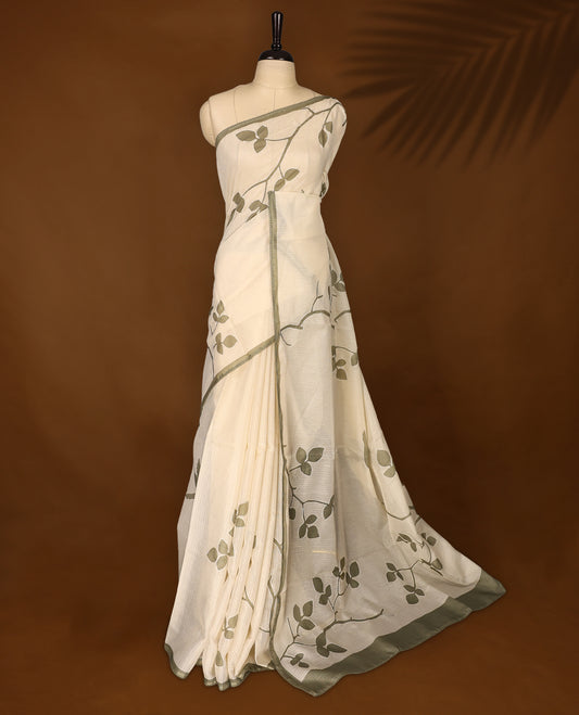 Cream colour Tussar cotton Kota saree featuring elegant Olive green leafy branch motifs across the body, accentuated with a subtle Olive green border, and paired with a matching blouse for a graceful and minimal look.