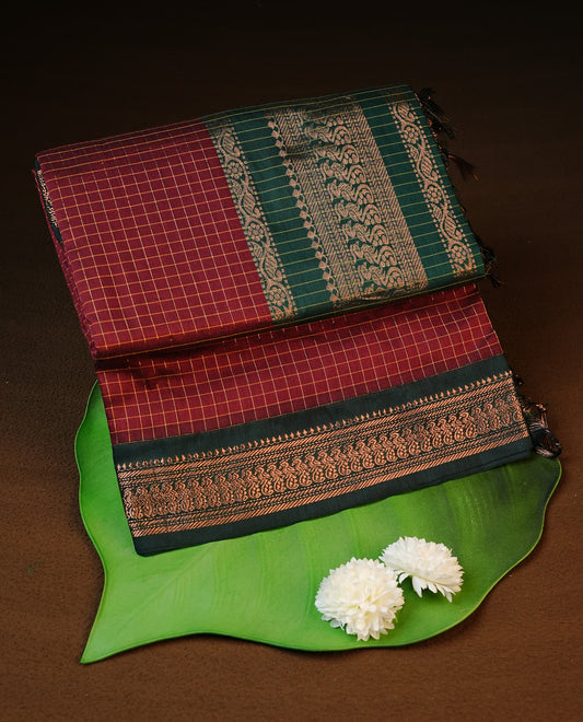 Maroon colour kalyani cotton saree featuring gold zari check pattern on body, complemented by green colour with Antique zari border, paired with matching blouse piece.