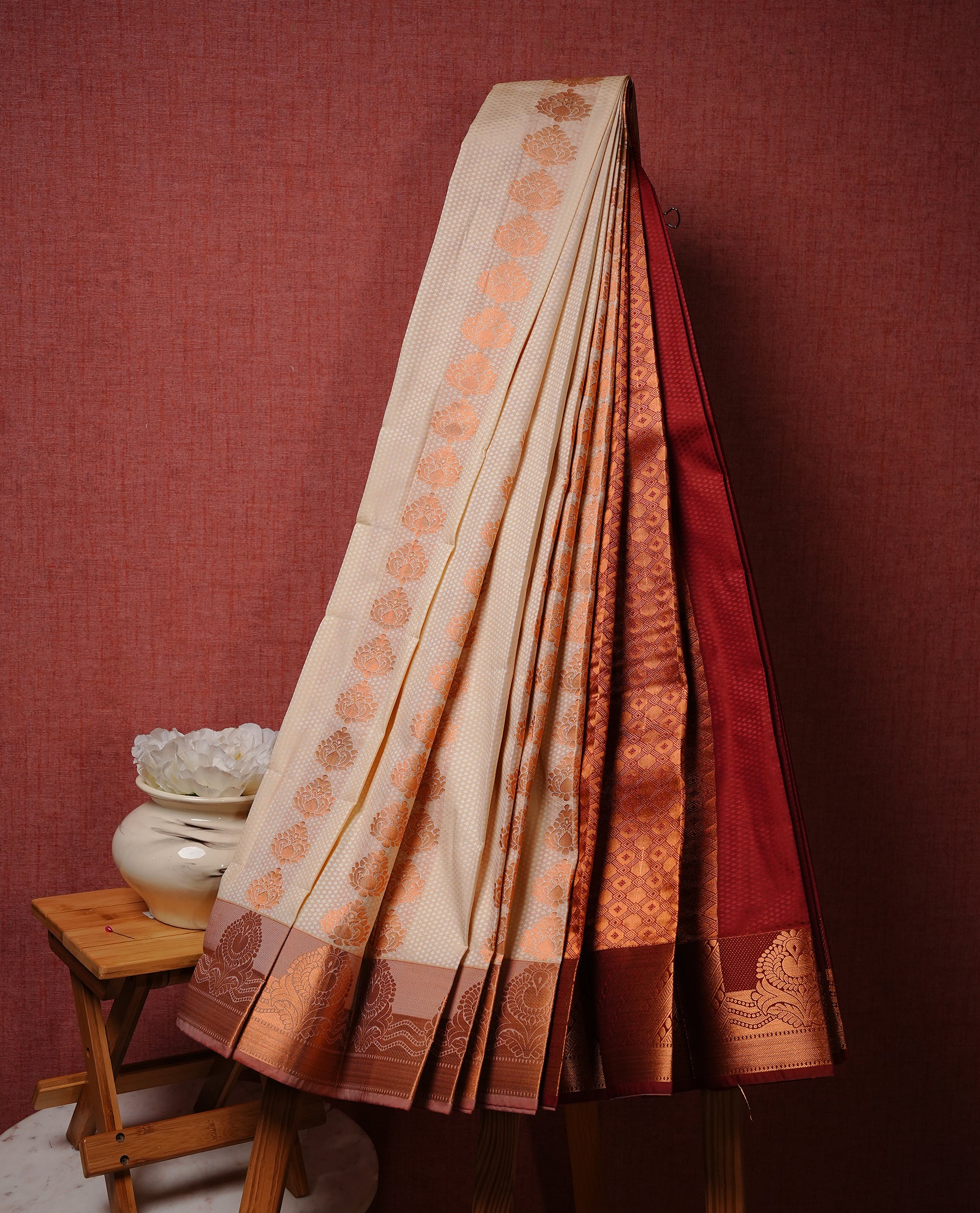 Off white colour Semi silk saree Featuring gold zari motifs on body, complemented by contrast pale orange colour with gold zari border, paired with matching blouse piece.