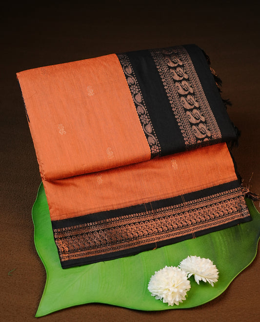 Orange colour kalyani cotton saree featuring antique zari motifs on body, complemented by Black colour with Antique zari border, paired with matching blouse piece.