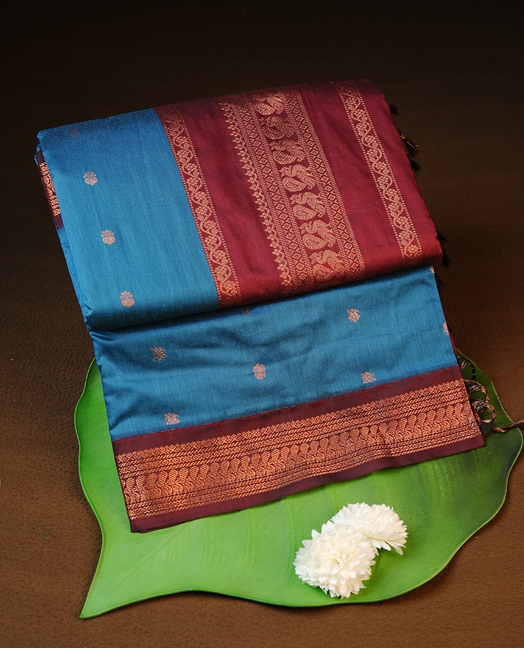 Blue colour kalyani cotton saree featuring antique zari motifs on body, complemented by Maroon colour with Antique zari border, paired with matching blouse piece.