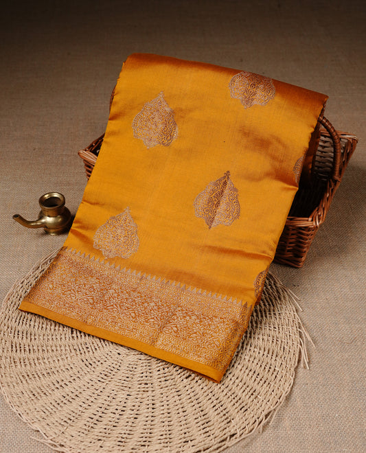 Mustard Colour Pure Banaras Soft Silk saree featuring Antique Zari buttas in body, complemented by zari work on self colour border, paired with matching Blouse Piece.