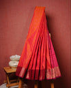 Orange colour Semi silk saree Featuring selfcolour zari motifs on body, complemented by contrast Magenta colour with gold zari border, paired with matching blouse piece.